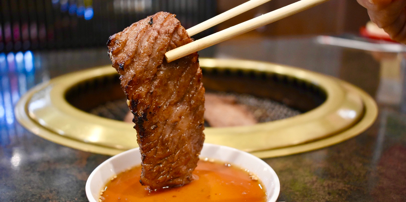 焼肉をタレにつけている様子